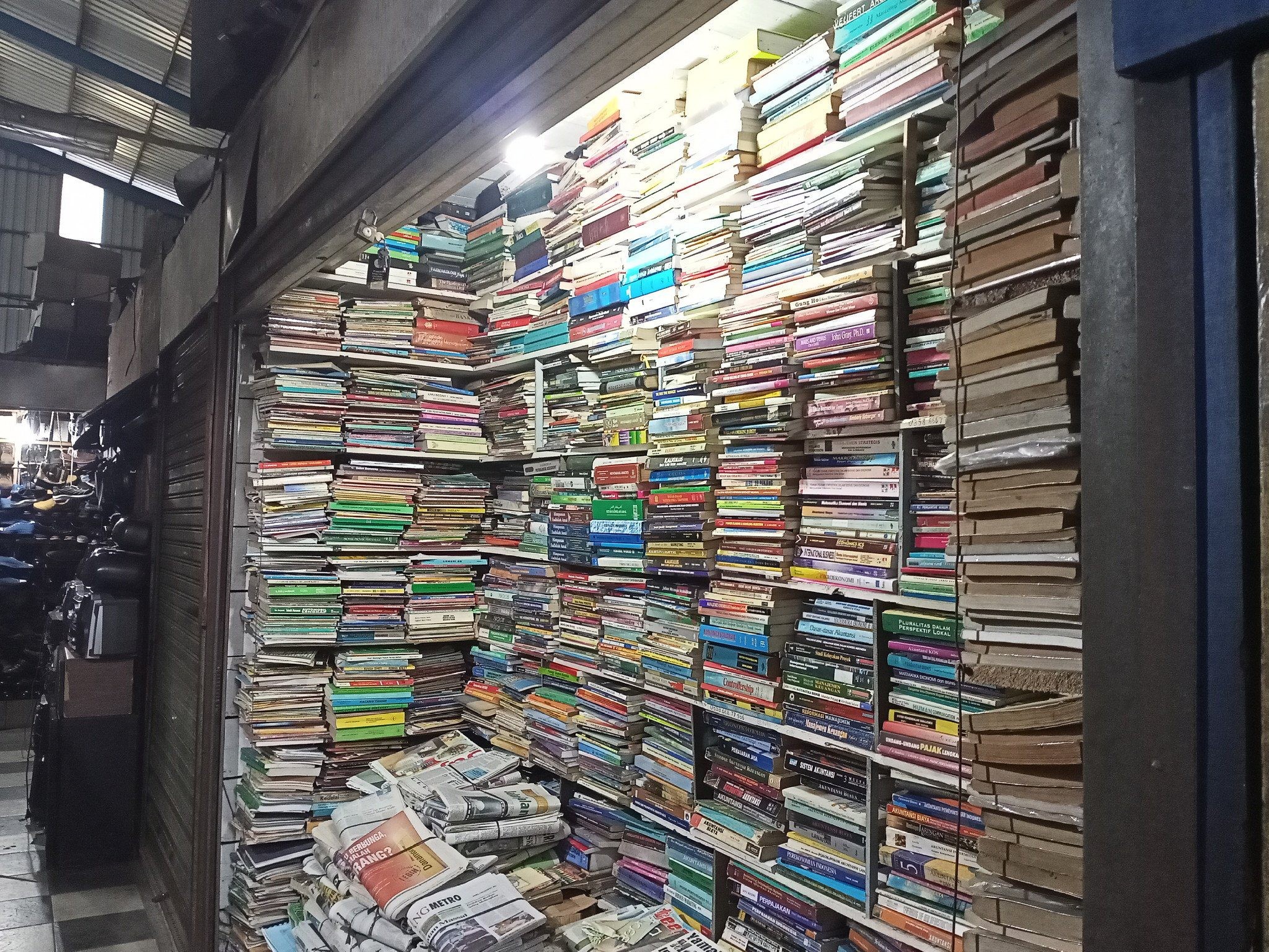 Pemilik kios buku loak sedang meneliti tumpukan buku sastra yang dibawa oleh penjual di kardus.